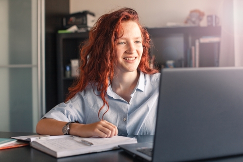 Caucasian teen girl college student taking online training class on laptop computer, woman sitting at university table. Virtual education webinar, remote study, distance academic learning.
