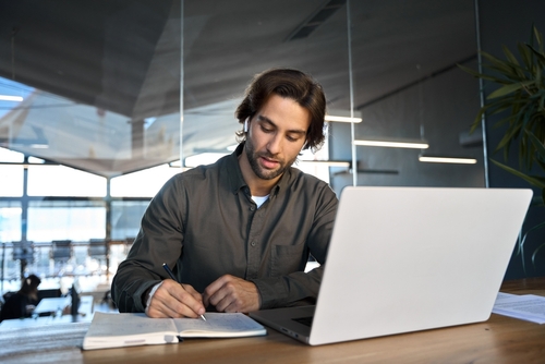 A person in a suit typing on a laptop.